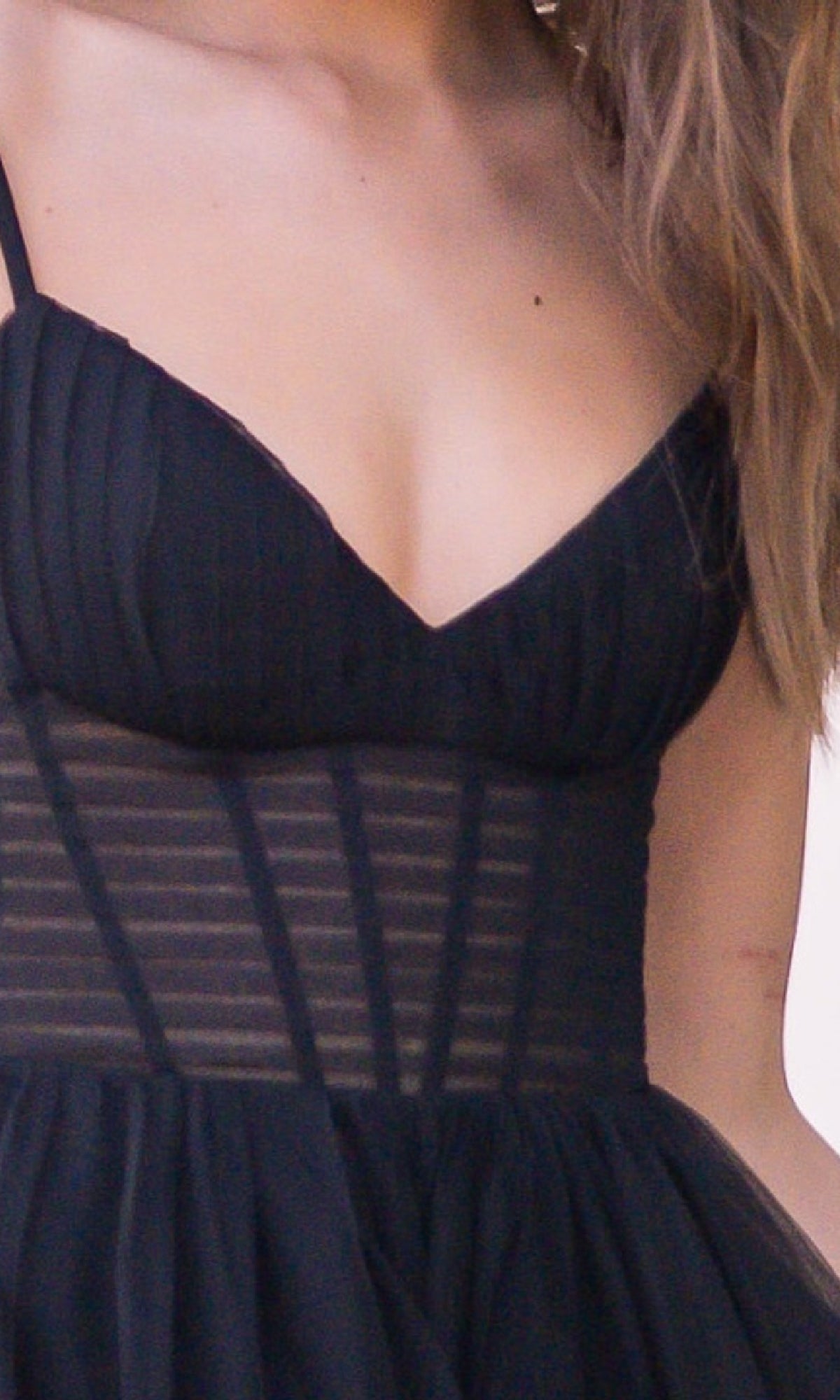 A woman wearing the Yasmin by Velvi Sheer-Corset Long Prom Ball Gown, an affordable sleeveless black dress with a sheer striped midsection and fitted bodice.